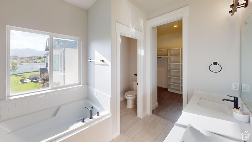 Bathroom featuring sink, tile flooring, a relaxing tiled bath, and toilet