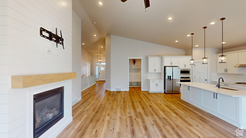 Kitchen featuring ceiling fan, light hardwood / wood-style floors, tasteful backsplash, hanging light fixtures, and appliances with stainless steel finishes