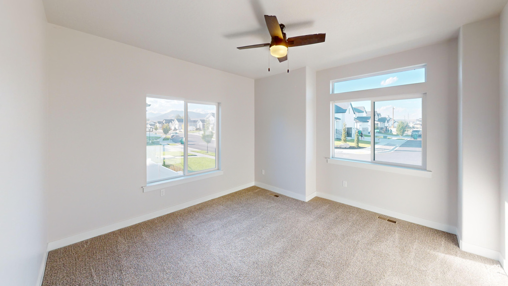 Carpeted empty room with ceiling fan