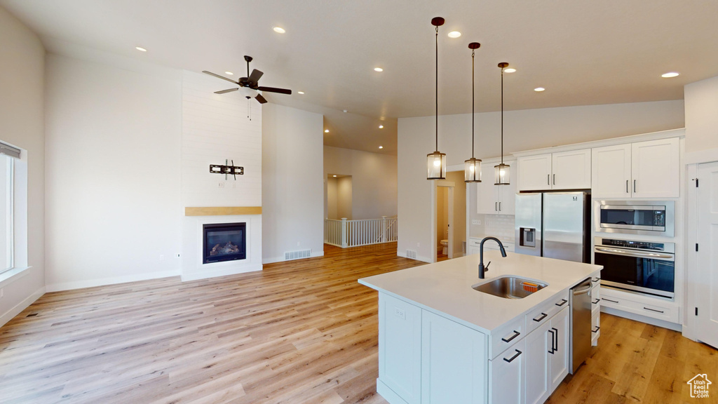 Kitchen with light hardwood / wood-style floors, sink, white cabinets, and stainless steel appliances