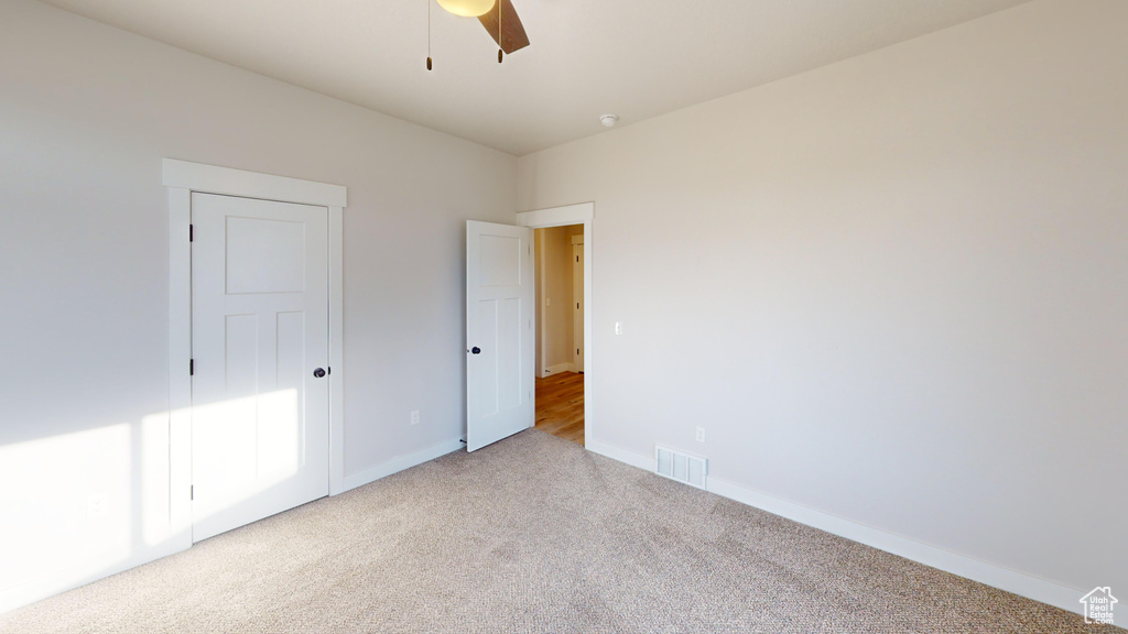 Unfurnished bedroom featuring light carpet and ceiling fan