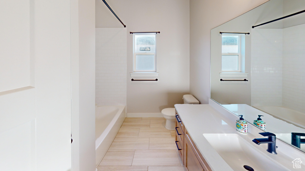 Full bathroom featuring oversized vanity, a wealth of natural light, toilet, and tiled shower / bath combo