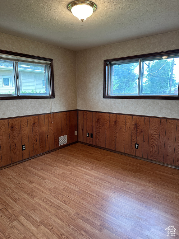 Empty room featuring light wood-type flooring and a textured ceiling