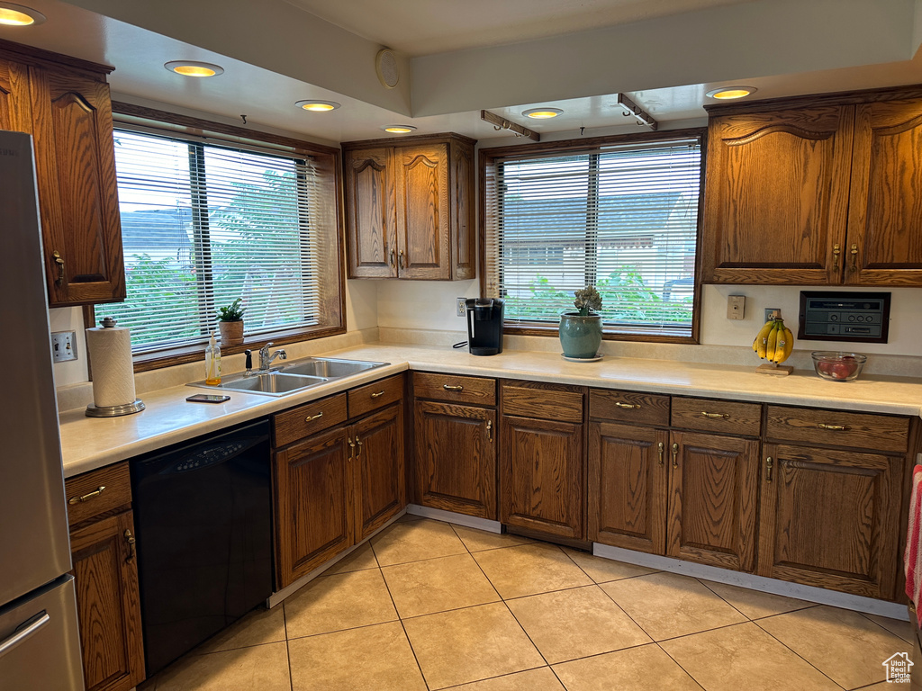 Kitchen featuring black dishwasher, stainless steel fridge, light tile patterned flooring, and sink