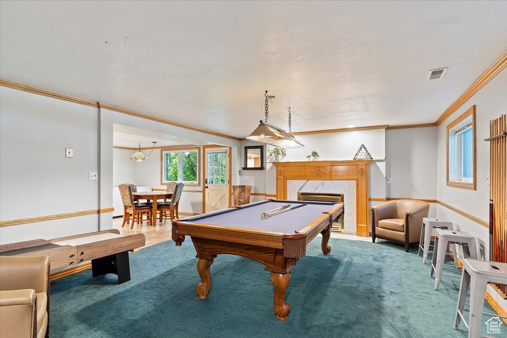 Game room with a high end fireplace, ornamental molding, carpet flooring, and billiards