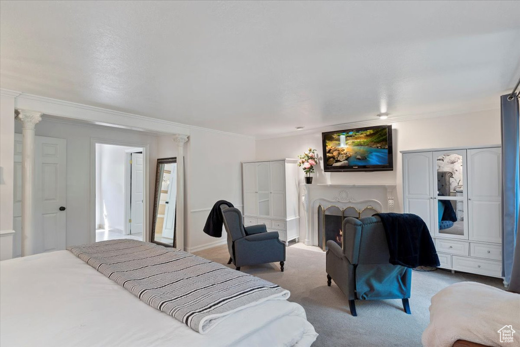 Carpeted bedroom featuring decorative columns and crown molding