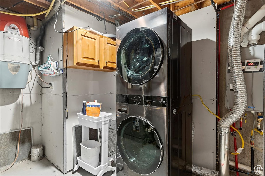 Washroom featuring stacked washer / dryer and cabinets