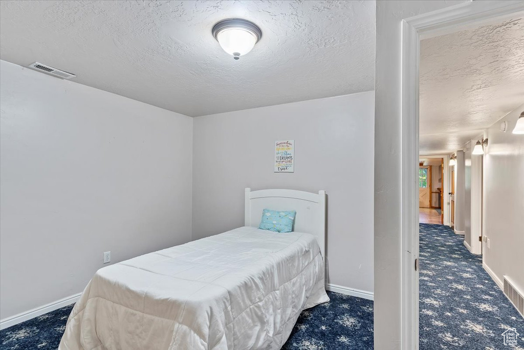 Bedroom featuring dark carpet and a textured ceiling