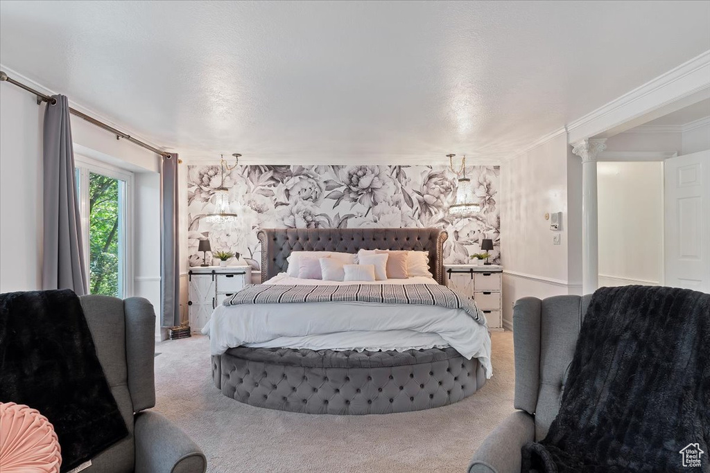 Carpeted bedroom featuring decorative columns and crown molding