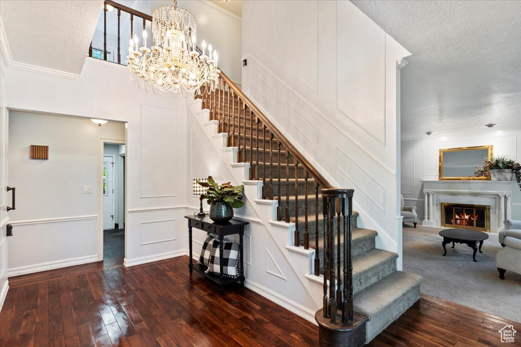 Stairway featuring a textured ceiling, ornamental molding, hardwood / wood-style floors, and an inviting chandelier