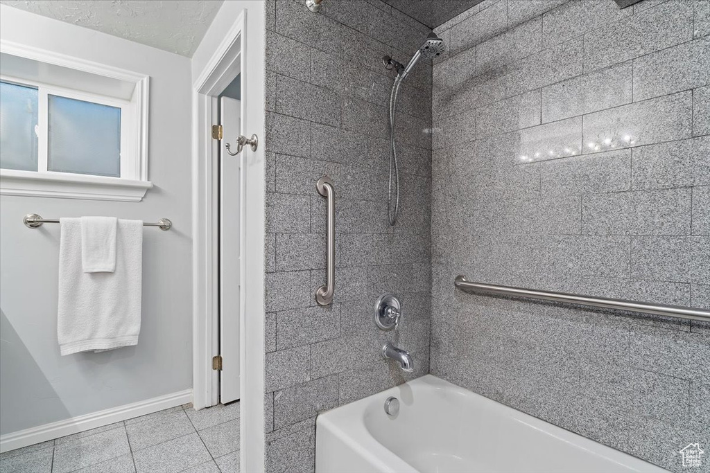 Bathroom featuring a textured ceiling, tiled shower / bath combo, and tile patterned floors