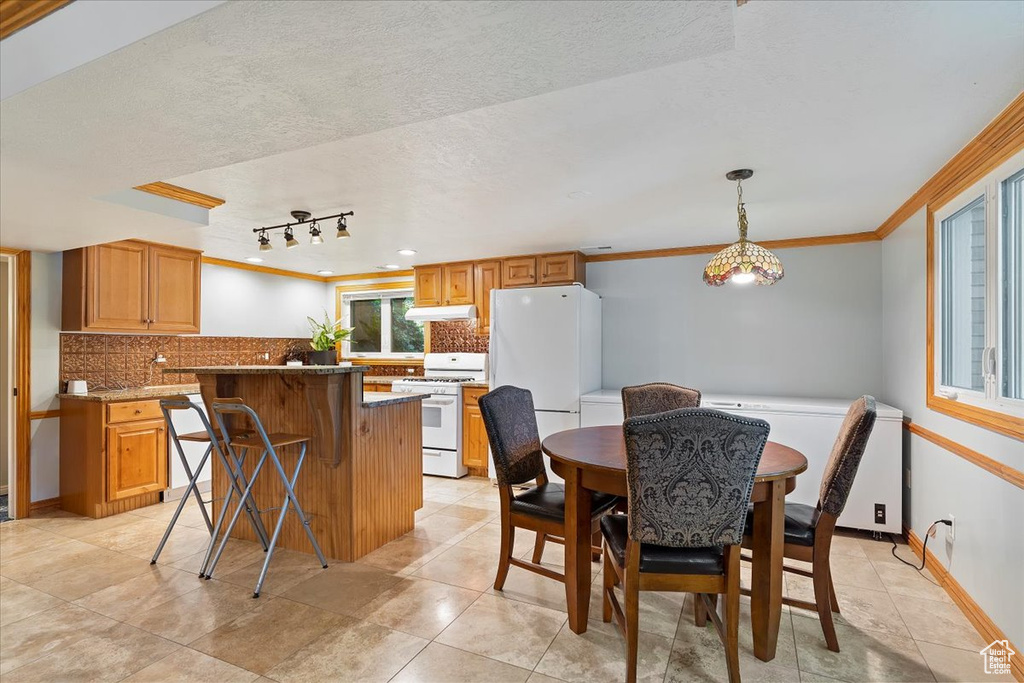 Kitchen with a kitchen island, a textured ceiling, tasteful backsplash, and white appliances