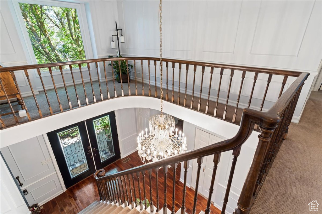 Staircase featuring french doors, dark hardwood / wood-style flooring, and a notable chandelier