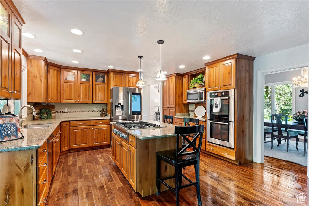 Kitchen with appliances with stainless steel finishes, sink, dark hardwood / wood-style floors, a center island, and a chandelier