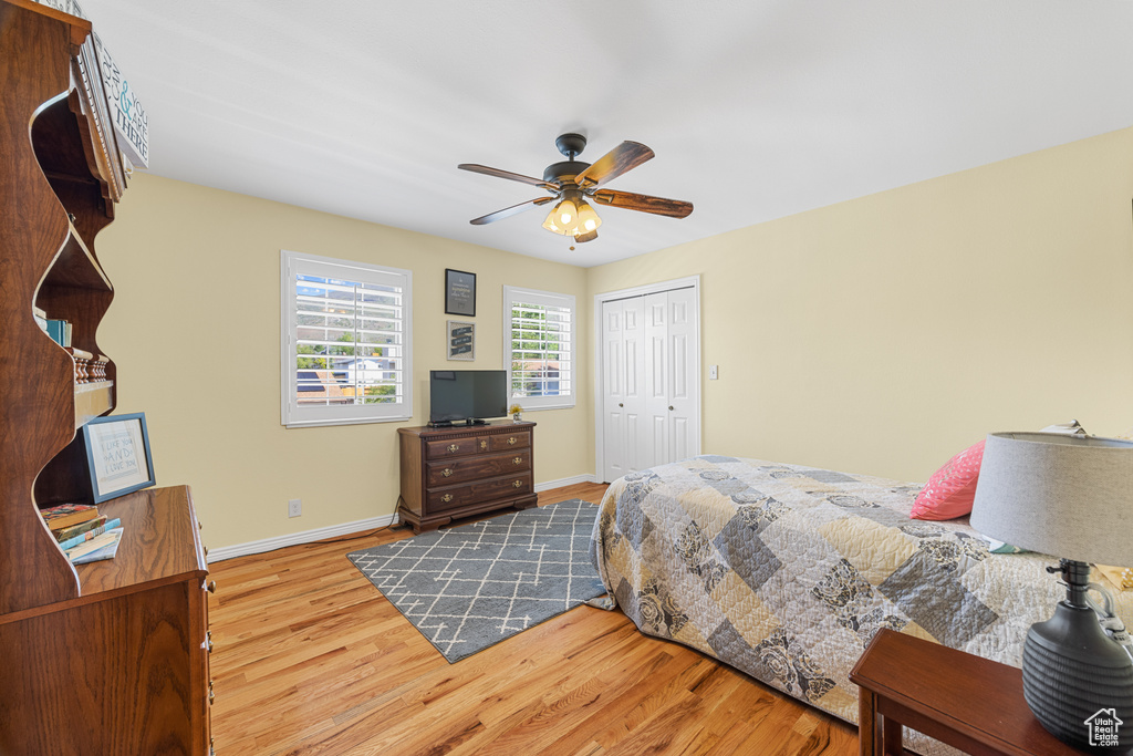 Bedroom with light hardwood / wood-style floors, a closet, and ceiling fan