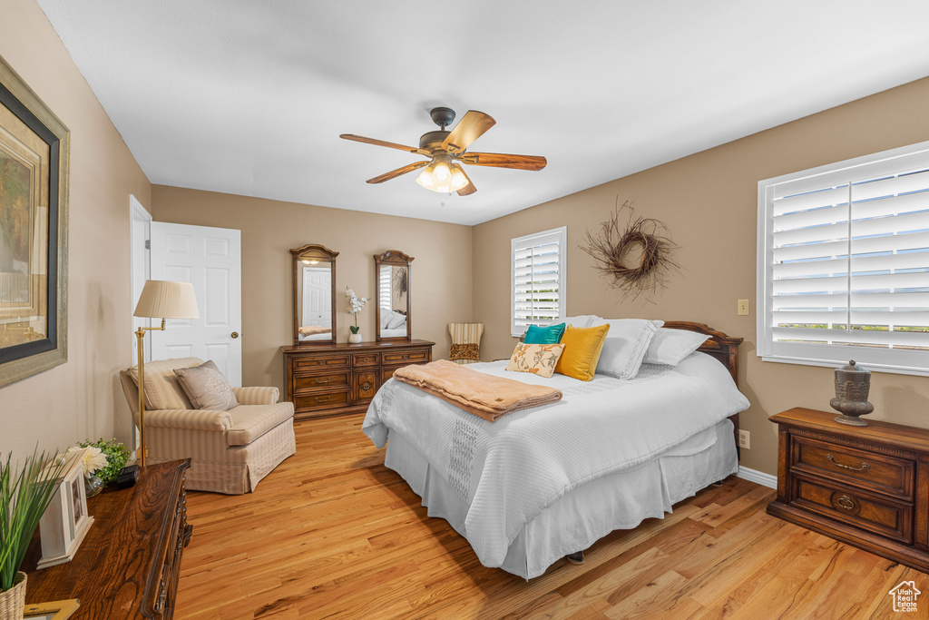 Bedroom with multiple windows, light wood-type flooring, and ceiling fan