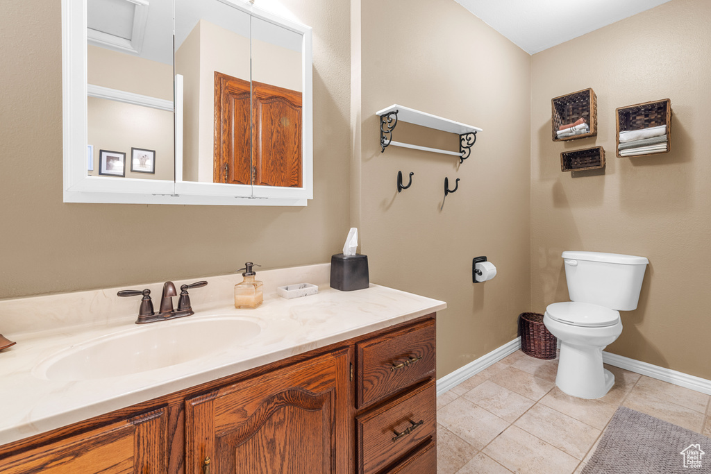 Bathroom with vanity, toilet, and tile patterned flooring