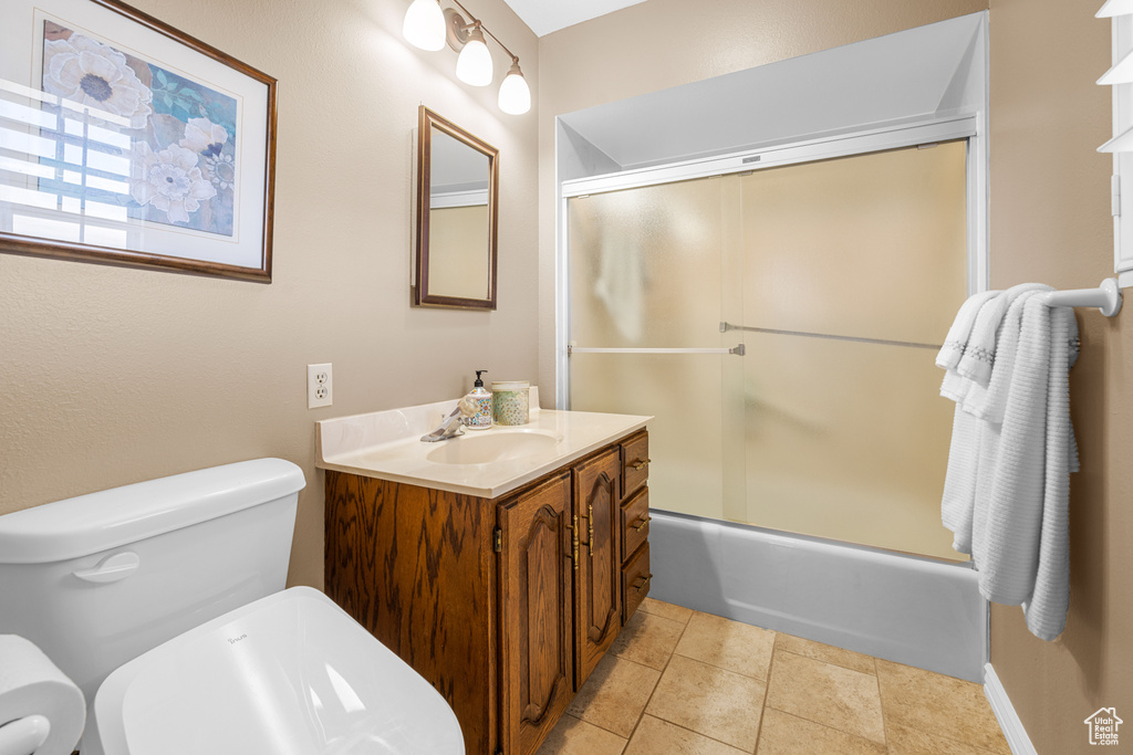 Full bathroom featuring tile patterned flooring, combined bath / shower with glass door, toilet, and vanity