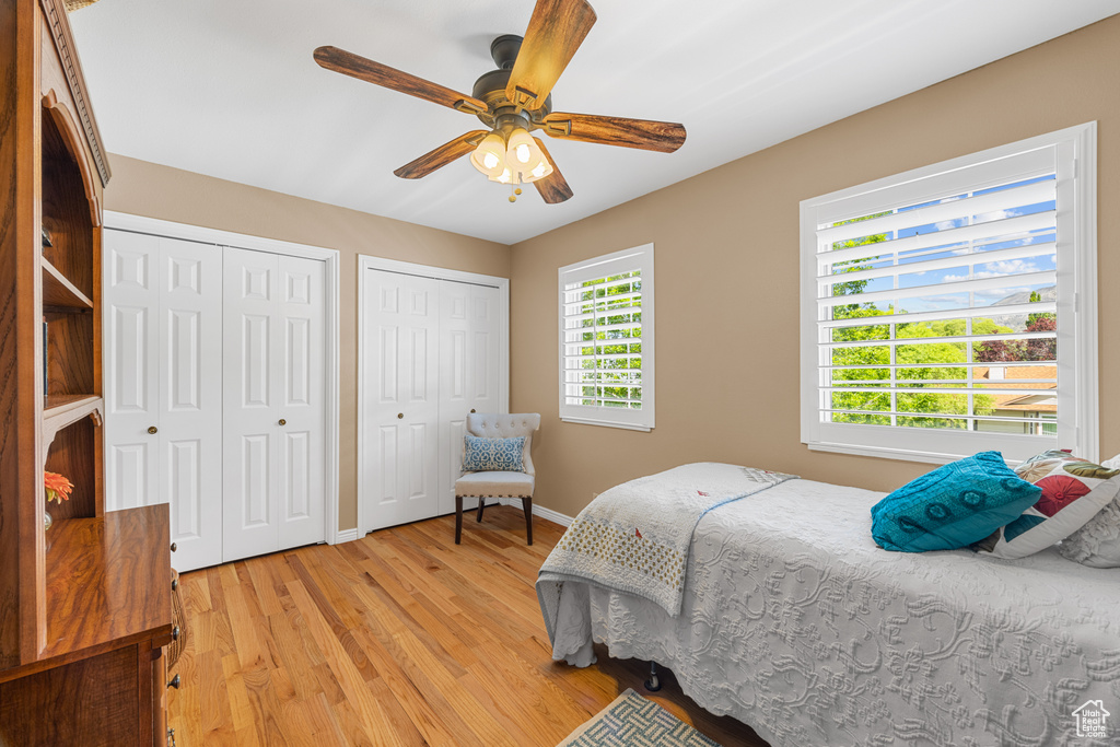 Bedroom featuring multiple closets, light hardwood / wood-style floors, and ceiling fan