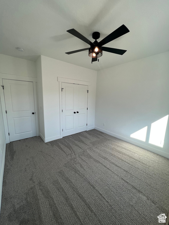 Unfurnished bedroom featuring dark carpet, a closet, and ceiling fan