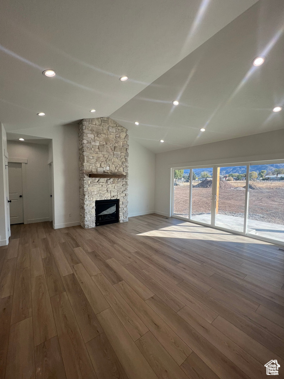 Unfurnished living room featuring a stone fireplace and hardwood / wood-style flooring