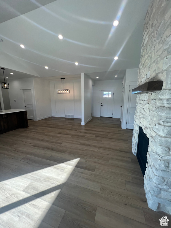 Unfurnished living room featuring a stone fireplace and dark wood-type flooring