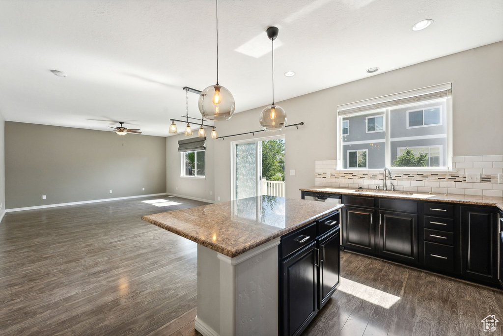 Kitchen featuring a center island, dark hardwood / wood-style floors, ceiling fan, and backsplash