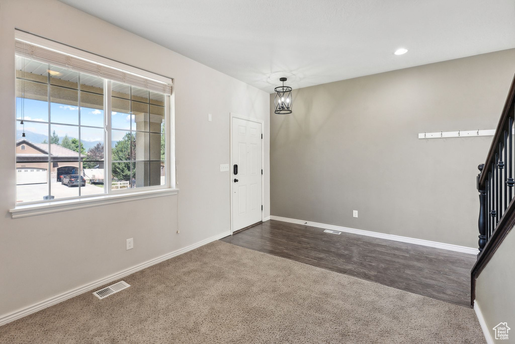 Foyer entrance with a notable chandelier and dark hardwood / wood-style floors