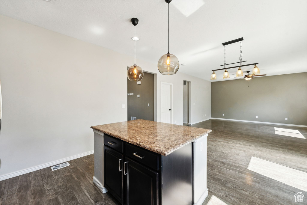 Kitchen with a kitchen island, ceiling fan, hardwood / wood-style flooring, and hanging light fixtures