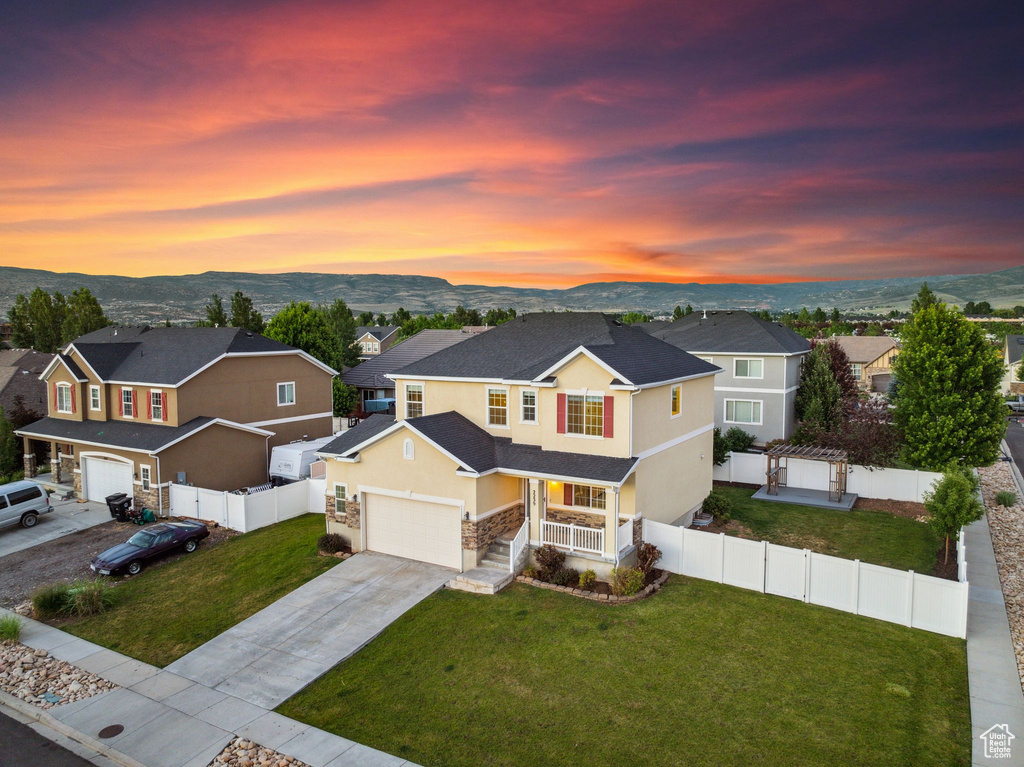 View of front of home featuring a garage, a yard, and a mountain view