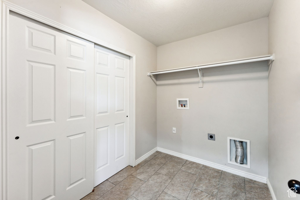 Laundry room with hookup for a washing machine, electric dryer hookup, and light tile patterned floors