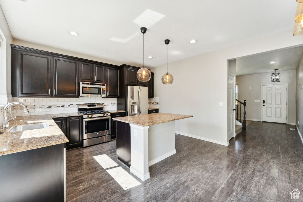 Kitchen with tasteful backsplash, a center island, dark hardwood / wood-style floors, stainless steel appliances, and hanging light fixtures