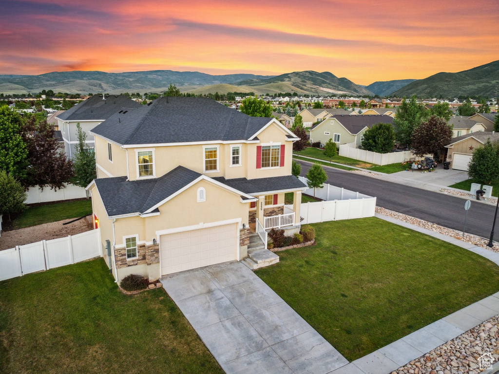 View of front of home with a mountain view, a garage, and a lawn