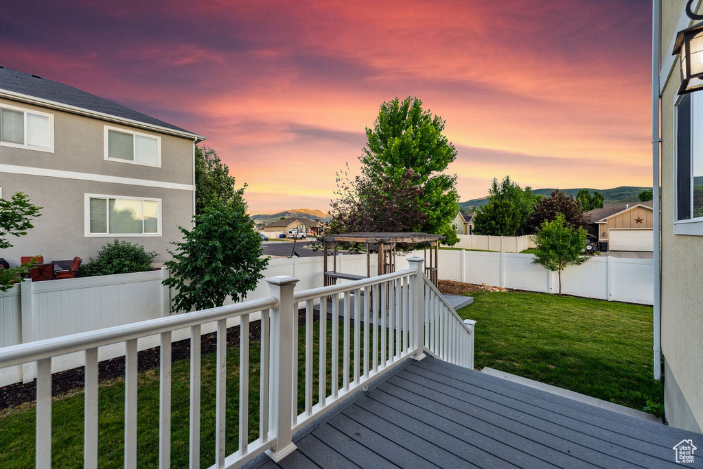 Deck at dusk featuring a lawn