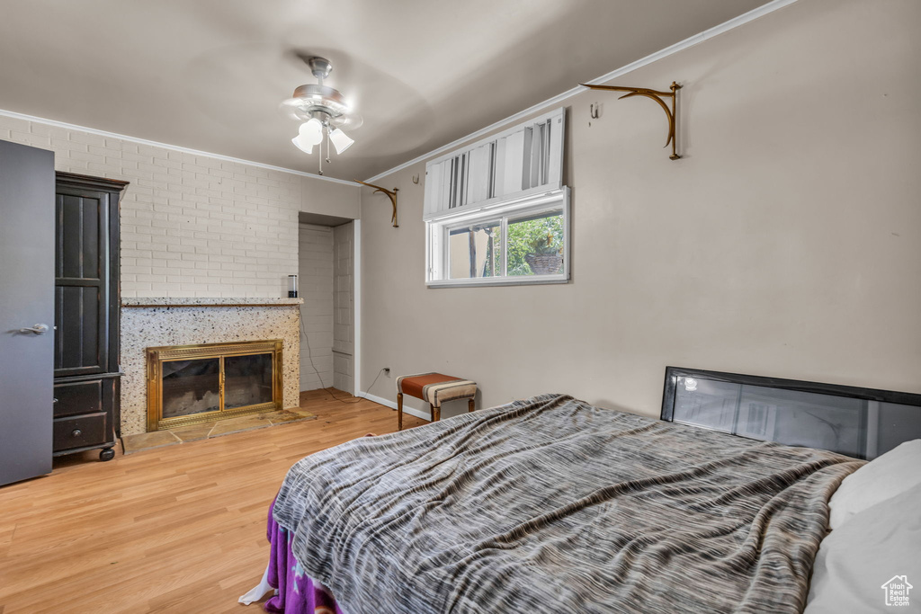 Bedroom with ceiling fan, brick wall, hardwood / wood-style flooring, and ornamental molding