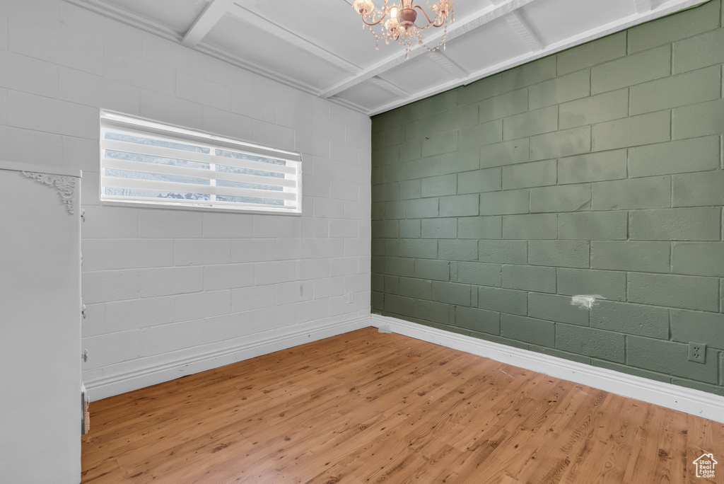 Unfurnished room with a notable chandelier, wood-type flooring, and coffered ceiling