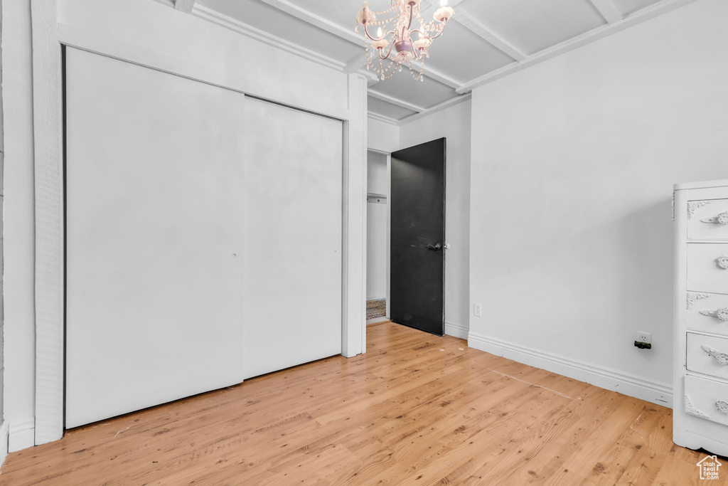 Unfurnished bedroom with light hardwood / wood-style floors and a chandelier