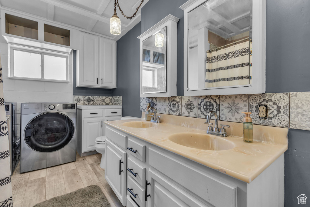 Laundry room featuring washer / dryer, sink, plenty of natural light, and light hardwood / wood-style floors