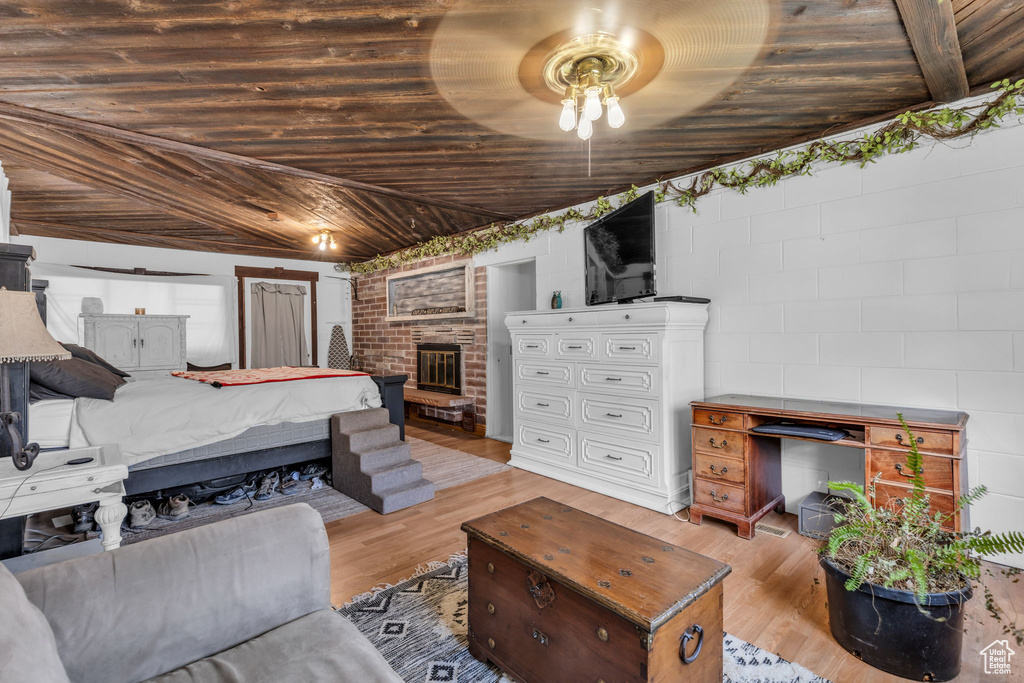 Bedroom featuring light wood-type flooring, a fireplace, wooden ceiling, and ceiling fan