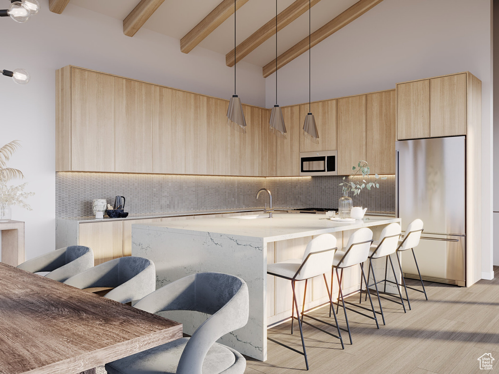 Kitchen with light brown cabinetry, stainless steel appliances, pendant lighting, high vaulted ceiling, and light hardwood / wood-style flooring