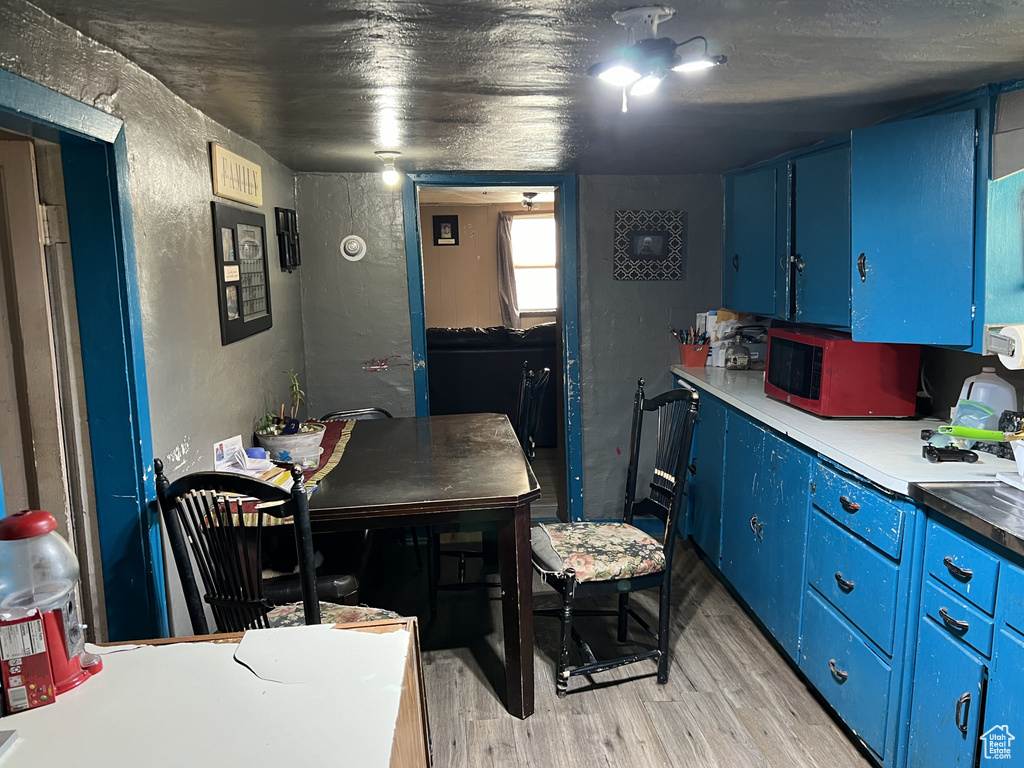 Kitchen with light countertops, blue cabinetry, light wood finished floors, and a textured wall