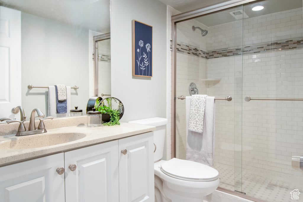 Bathroom with a shower with door, vanity, and toilet