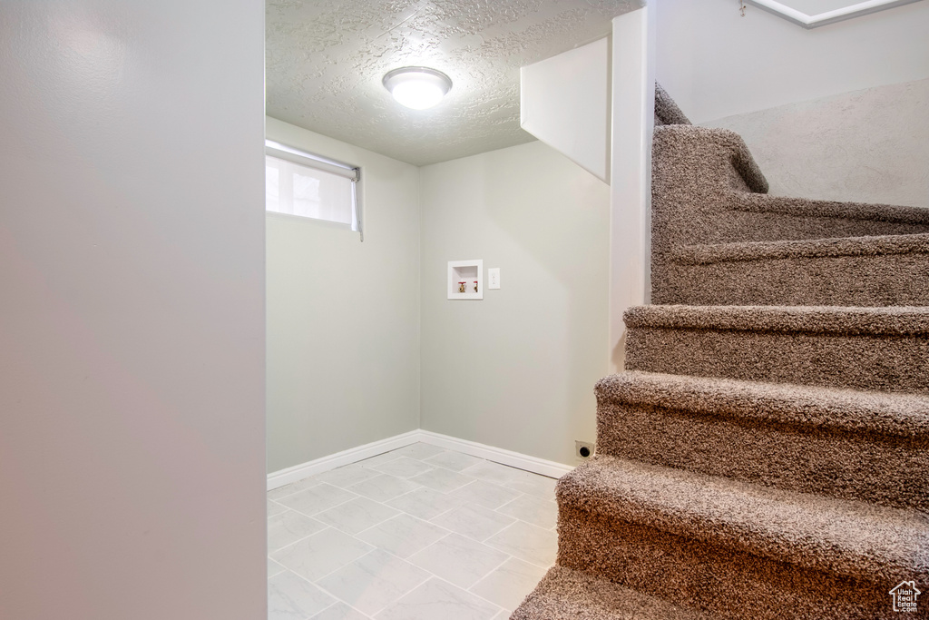 Stairway with a textured ceiling and tile patterned floors