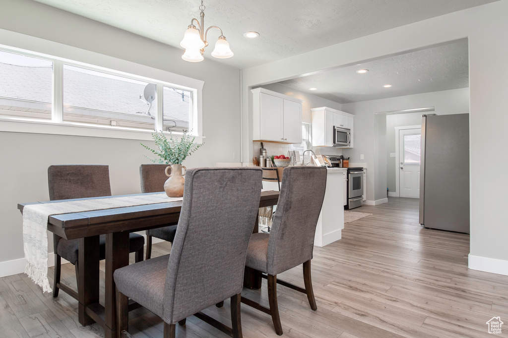 Dining area with a notable chandelier and light hardwood / wood-style flooring