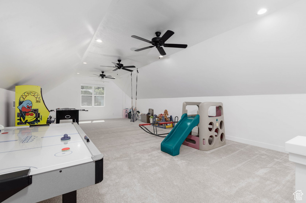 Recreation room featuring light carpet, ceiling fan, and vaulted ceiling