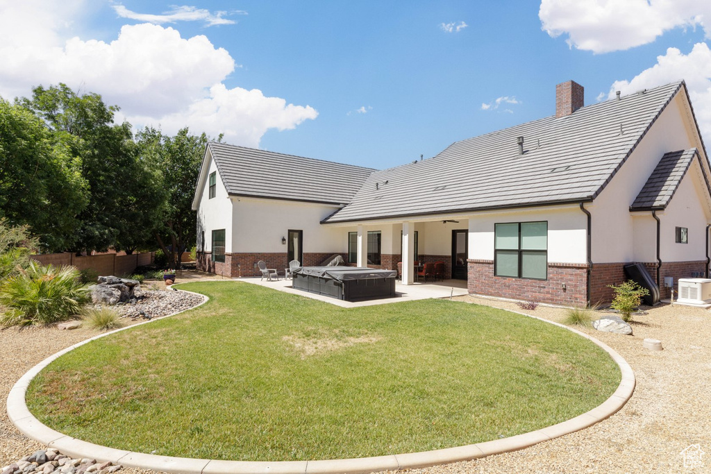 Back of property with central AC, a lawn, and a patio area