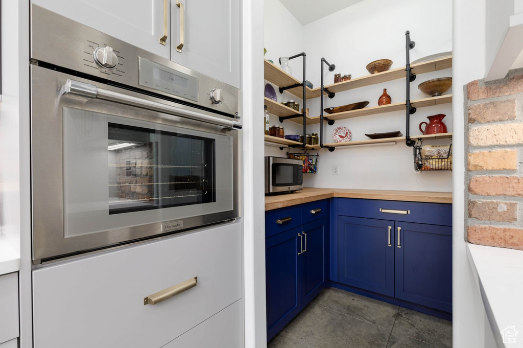 Kitchen featuring wooden counters, light tile patterned flooring, blue cabinets, and stainless steel appliances