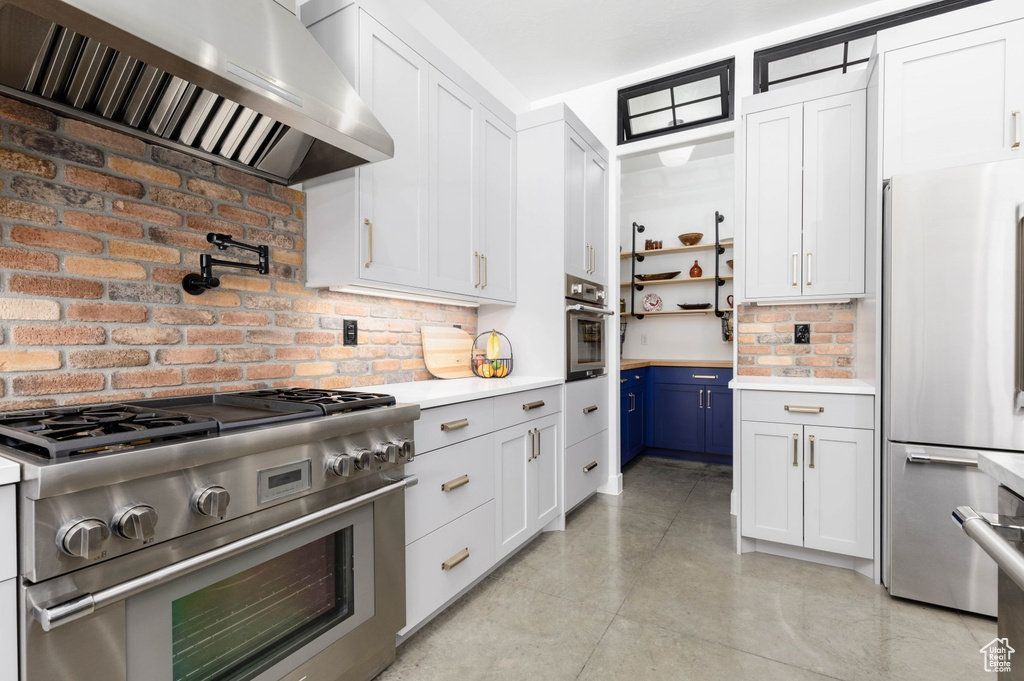 Kitchen with white cabinetry, tasteful backsplash, stainless steel appliances, and wall chimney exhaust hood