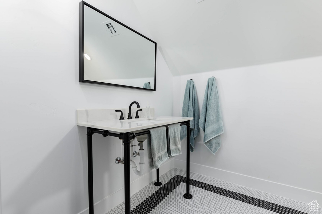 Bathroom featuring lofted ceiling and sink