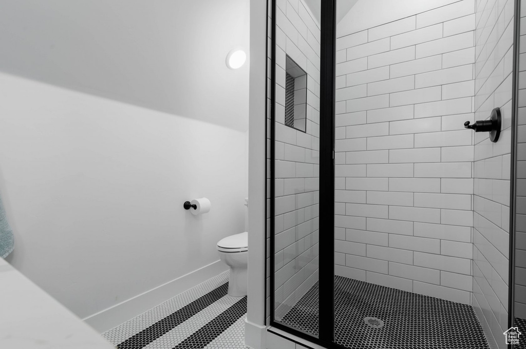 Bathroom featuring tiled shower, tile patterned flooring, and toilet